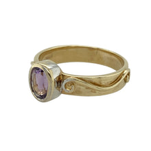 Load image into Gallery viewer, Bring vibrant colour and elegant heritage style to your collection with this pre-owned 9ct yellow gold Clogau swirl ring set with amethyst—a meaningful design with timeless charm.

Design: The ring showcases a 7mm by 5mm oval amethyst at the centre, held within a flowing swirl design for a graceful and eye-catching look.
Material: Made from 9-carat yellow gold, the polished finish enhances the warm tone of the gold and the rich purple of the amethyst.

