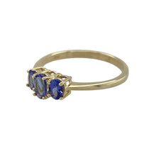 Load image into Gallery viewer, Bring refined colour and delicate elegance to your collection with this pre-owned 9ct yellow gold tanzanite trilogy ring, offering subtle sparkle and timeless sophistication—perfect for everyday wear or special occasions.

Design: Showcasing a trilogy of oval tanzanite stones, the centre measuring 5mm by 3mm and flanked by two 4mm by 2mm stones, the ring creates a balanced and graceful look with soft violet-blue hues.

