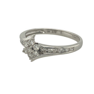 Bring sparkling elegance and timeless charm to your collection with this pre-owned 9ct white gold diamond flower cluster twist ring—a graceful design with refined brilliance.

Design: The ring features a 9mm high floral cluster of diamonds at the centre, complemented by diamond-set shoulders and a subtle twist design for added detail.
Material: Made from 9-carat white gold, the polished finish enhances the brilliance of the diamonds and adds modern appeal.
