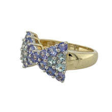 Load image into Gallery viewer, Bring colourful sparkle and playful elegance to your collection with this pre-owned 9ct yellow gold tanzanite and blue topaz cluster ring, designed in a charming bow style—perfect for special occasions or vibrant everyday wear.

Design: The ring showcases a bow-shaped cluster of alternating 2mm round tanzanite and blue topaz stones, with the front of the design measuring 11mm high for a striking presence.

