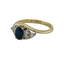 Load image into Gallery viewer, Bring timeless elegance and refined sparkle to your collection with this pre-owned 18ct yellow gold sapphire and diamond twist ring, combining classic gemstones with a graceful design—perfect for both everyday wear and special occasions.

Design: The ring features a 6mm by 4mm oval sapphire at the centre, accented by clusters of small diamonds on either side, arranged in a flowing twist setting for added movement and style.

