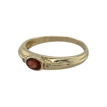 Load image into Gallery viewer, Bring warmth and classic charm to your collection with this pre-owned 9ct yellow gold diamond and garnet band ring, offering a touch of rich colour and subtle sparkle—perfect for everyday wear or marking a special occasion.

Design: The ring features a 5mm by 4mm oval-cut garnet at its centre, accented with sparkling diamonds that enhance the gemstone’s deep red tones for an elegant and timeless look.

