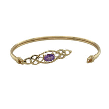 Load image into Gallery viewer, Celebrate heritage and elegance with this pre-owned 9ct yellow gold amethyst Celtic knot bangle, combining timeless design with vibrant colour—perfect for both everyday wear and special occasions.

Design: The bangle features an intricate Celtic knot motif centred with a 7mm by 5mm oval-cut amethyst, adding a touch of rich purple sparkle to the meaningful design.
Material: Made from 9-carat yellow gold, the polished finish enhances the warmth of the gold and complements the gemstone’s vivid hue.


