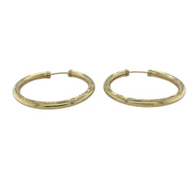 Load image into Gallery viewer, Bring texture and classic shine to your collection with these pre-owned 9ct yellow gold patterned hollow hoop earrings—a timeless style with elegant detailing.

Design: Each earring features a traditional hoop shape with a subtle patterned finish, adding depth and interest to the polished gold surface.
Material: Made from 9-carat yellow gold, the polished finish enhances the warm tone and highlights the decorative patterning.
