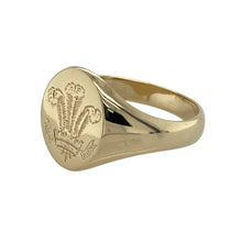 Load image into Gallery viewer, Bring heritage and distinctive style to your collection with this pre-owned 9ct yellow gold Welsh three feathers signet ring—a meaningful design with timeless appeal.

Design: The ring features an oval face measuring 15mm high, engraved with the iconic Welsh three feathers motif for a bold and traditional look.
Material: Made from 9-carat yellow gold, the polished finish enhances the warm tone and highlights the detailed emblem.
