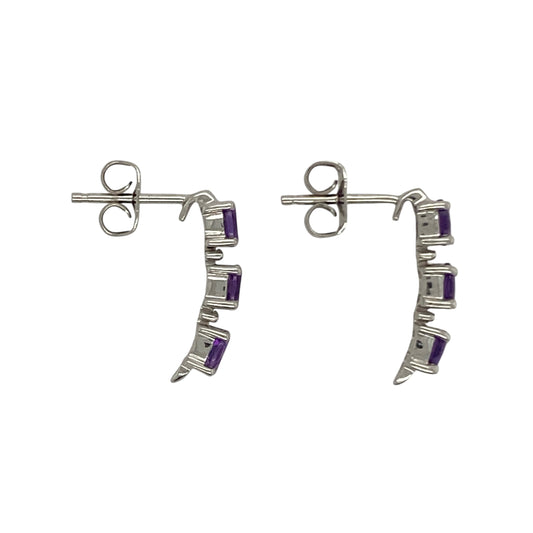 Bring vibrant colour and refined sparkle to your collection with these pre-owned 9ct white gold amethyst and diamond drop stud earrings—a graceful design with timeless charm.

Design: Each earring features three oval amethyst stones measuring 4mm by 3mm, arranged vertically with a small diamond set between each stone for added brilliance.
Material: Made from 9-carat white gold, the polished finish enhances the bright tone and beautifully complements the rich purple of the amethysts.