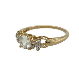 Bring delicate sparkle and feminine charm to your collection with this pre-owned 9ct yellow gold ring, styled with floral shoulder detailing and a brilliant cubic zirconia centre.

Design: The ring features a 5mm round cubic zirconia at the centre, complemented by flower motifs on each shoulder for a refined and graceful look.
Material: Made from 9-carat yellow gold, the polished finish enhances the warm tone and sets off the brilliance of the stone.