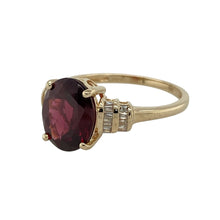 Load image into Gallery viewer, Bring rich colour and timeless elegance to your collection with this pre-owned 9ct yellow gold ring, featuring a bold garnet accented with sparkling diamonds.

Design: The ring showcases a 10mm by 8mm oval garnet at the centre, framed by baguette-cut diamonds on each shoulder for a refined finish.
Material: Made from 9-carat yellow gold, the polished finish enhances the warm golden tone and complements the deep red garnet and bright diamonds.
