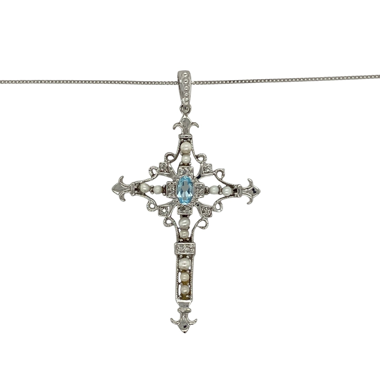 Bring colour, elegance, and meaning to your collection with this pre-owned 9ct white gold cross pendant, beautifully accented with diamonds, blue topaz, and a single pearl, complete with an 18" fine curb chain.

Design: The pendant showcases a 4.7cm long cross, including the bail, set with sparkling diamonds, vibrant blue topaz stones, and finished with a luminous pearl at the centre for a striking and symbolic look.