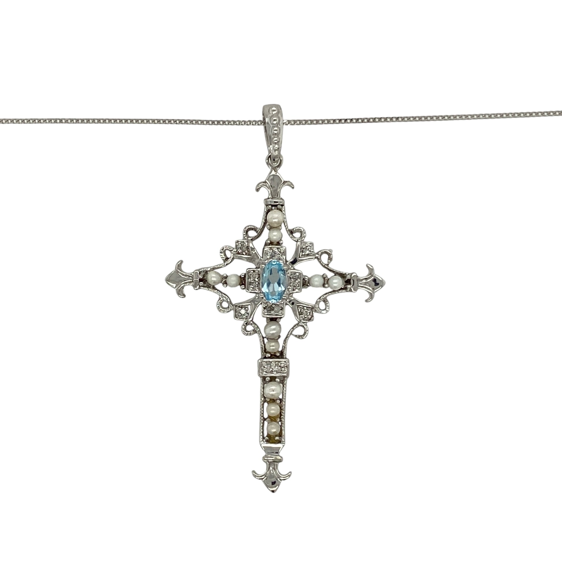 Bring colour, elegance, and meaning to your collection with this pre-owned 9ct white gold cross pendant, beautifully accented with diamonds, blue topaz, and a single pearl, complete with an 18" fine curb chain.

Design: The pendant showcases a 4.7cm long cross, including the bail, set with sparkling diamonds, vibrant blue topaz stones, and finished with a luminous pearl at the centre for a striking and symbolic look.
