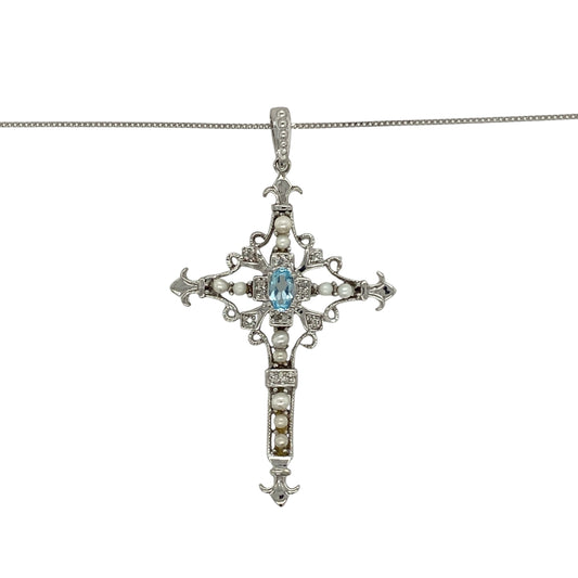 Bring colour, elegance, and meaning to your collection with this pre-owned 9ct white gold cross pendant, beautifully accented with diamonds, blue topaz, and a single pearl, complete with an 18" fine curb chain.

Design: The pendant showcases a 4.7cm long cross, including the bail, set with sparkling diamonds, vibrant blue topaz stones, and finished with a luminous pearl at the centre for a striking and symbolic look.