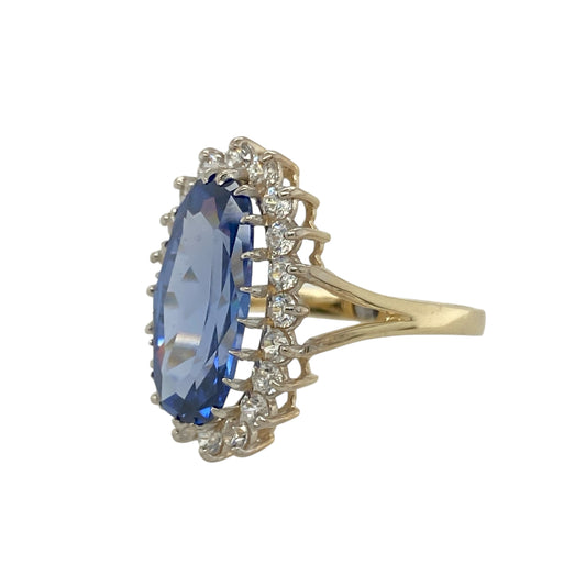 Bring vibrant sparkle and elegant colour to your collection with this pre-owned 9ct yellow gold cluster ring, featuring a striking light blue stone framed with cubic zirconia for timeless appeal.

Design: The ring showcases a 15mm by 7mm oval-cut light blue stone at the centre, surrounded by a cluster of cubic zirconia stones that add brilliance and contrast.
Material: Made from 9-carat yellow gold, the polished finish enhances the sparkle of the stones while providing a warm, refined tone.