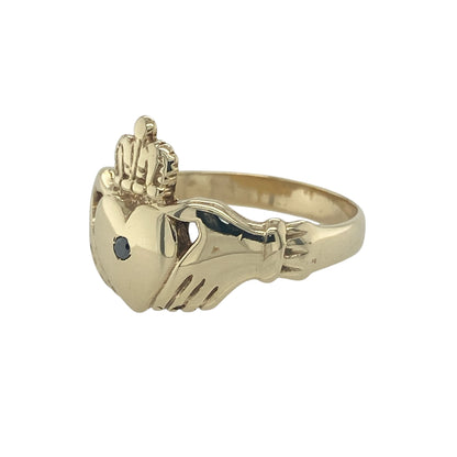 Bring symbolic meaning and striking detail to your collection with this pre-owned 9ct yellow gold black diamond Claddagh ring, a traditional design with a bold modern twist.

Design: The ring features the classic Claddagh motif—two hands holding a heart topped with a crown—measuring 15mm high, with a black diamond set at the centre for a distinctive finish.
Material: Made from 9-carat yellow gold, the polished band enhances the unique contrast of the dark gemstone against the warm gold.
