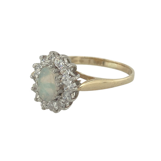 Bring shimmering colour and refined sparkle to your collection with this pre-owned 9ct yellow gold opalique and cubic zirconia cluster ring, a delicate design with timeless appeal.

Design: The ring features a 6mm by 4mm oval opalique stone at the centre, surrounded by cubic zirconia stones that enhance its iridescent tones with extra brilliance.
Material: Made from 9-carat yellow gold, the polished finish provides a warm contrast to the colourful play of the opalique