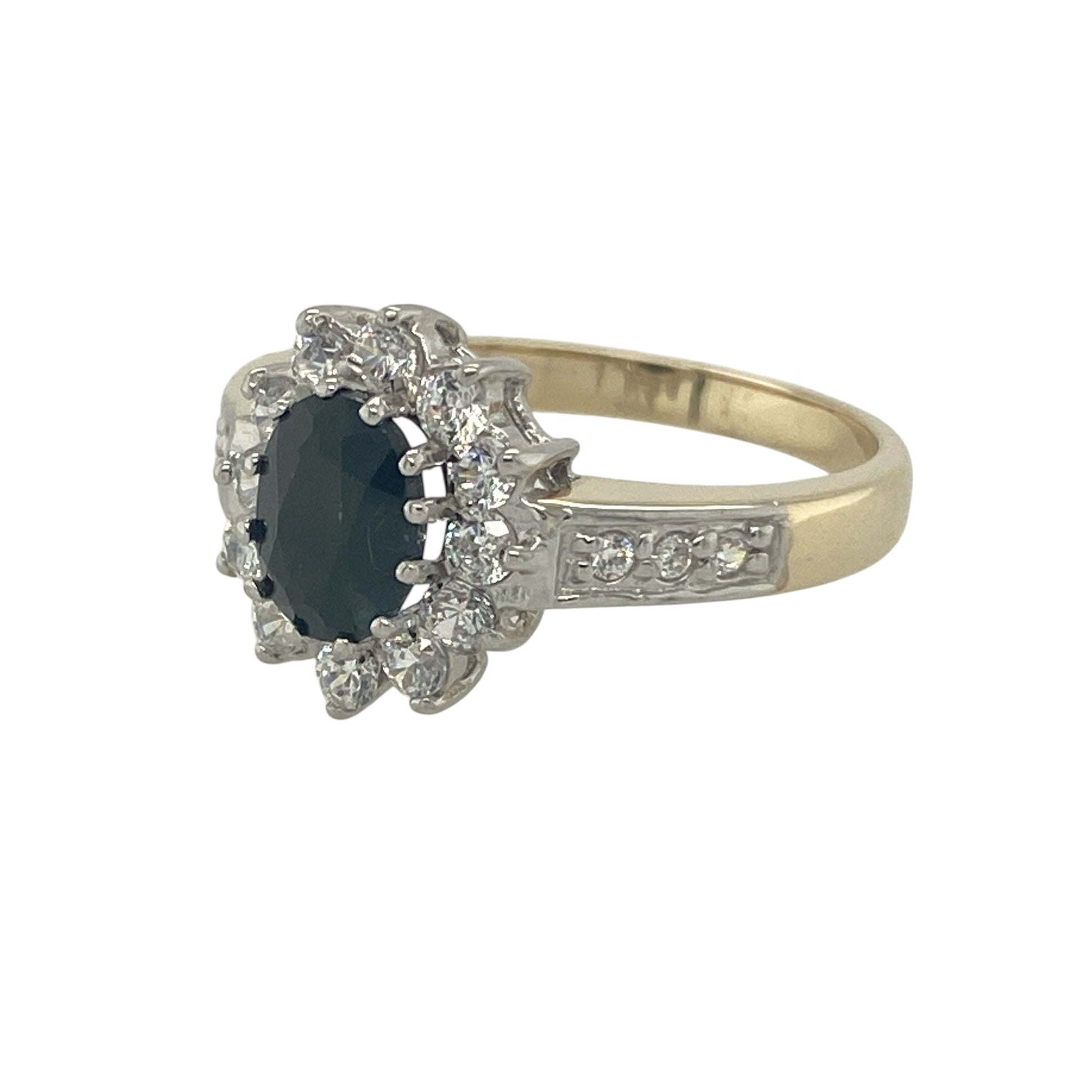 Bring timeless elegance and refined sparkle to your collection with this pre-owned 9ct yellow and white gold sapphire and cubic zirconia cluster ring, a classic design perfect for both everyday wear and special occasions.

Design: The ring features a 7mm by 5mm oval sapphire at the centre, surrounded by cubic zirconia stones and further accented along the shoulders for added brilliance. 