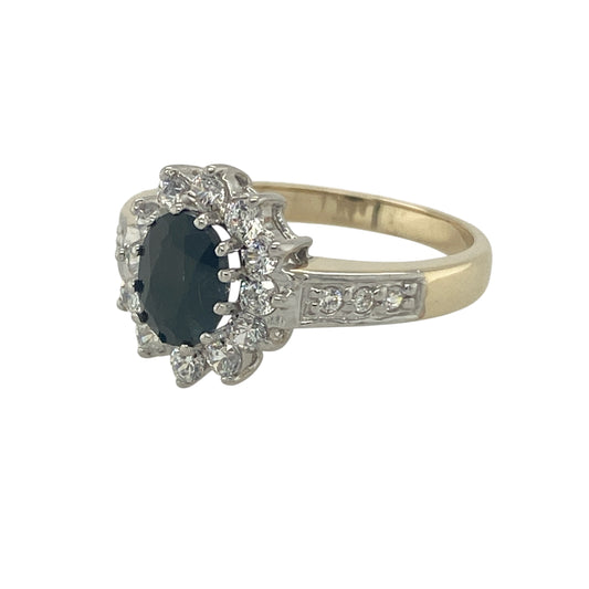 Bring timeless elegance and refined sparkle to your collection with this pre-owned 9ct yellow and white gold sapphire and cubic zirconia cluster ring, a classic design perfect for both everyday wear and special occasions.

Design: The ring features a 7mm by 5mm oval sapphire at the centre, surrounded by cubic zirconia stones and further accented along the shoulders for added brilliance. 
