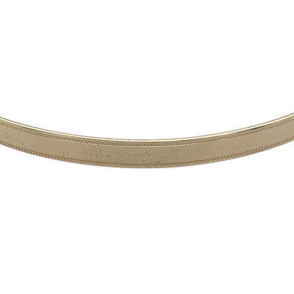 Bring refined elegance and timeless style to your collection with this pre-owned 9ct yellow solid gold milgrain edge bangle, a classic design with delicate detailing.

Design: The bangle features a smooth polished surface framed by fine milgrain edging, adding subtle texture and sophistication.
Material: Made from 9-carat solid yellow gold, the warm tone and polished finish highlight the intricate edging.