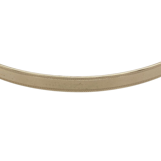 Bring refined elegance and timeless style to your collection with this pre-owned 9ct yellow solid gold milgrain edge bangle, a classic design with delicate detailing.

Design: The bangle features a smooth polished surface framed by fine milgrain edging, adding subtle texture and sophistication.
Material: Made from 9-carat solid yellow gold, the warm tone and polished finish highlight the intricate edging.