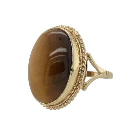 Bring natural beauty and bold detail to your collection with this pre-owned 9ct yellow gold and tiger’s eye oval ring, a striking design with timeless character.

Design: The ring showcases a 20mm by 15mm oval tiger’s eye stone framed by a rope-edge surround, highlighting the stone’s rich tones and unique chatoyancy.
Material: Made from 9-carat yellow gold, the polished finish enhances the warm setting and complements the golden-brown hues of the gemstone.