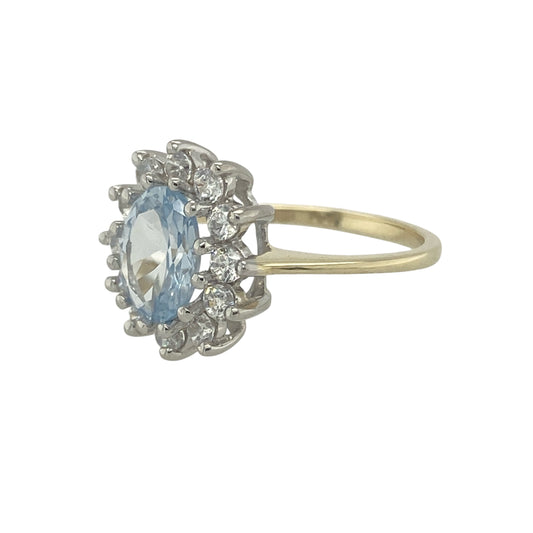 Bring soft colour and sparkling detail to your collection with this pre-owned 9ct yellow gold aqua and cubic zirconia cluster ring, a graceful design with timeless appeal.

Design: The ring features an 8mm by 6mm oval aqua stone at the centre, surrounded by glittering cubic zirconia in a classic cluster style for added brilliance.
Material: Made from 9-carat yellow gold, the polished finish enhances the warm tone and complements the cool hue of the aqua stone.