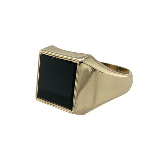 Bring bold style and classic design to your collection with this pre-owned 9ct yellow gold onyx signet ring—a timeless piece with strong presence and sophistication.

Design: The ring features a 12mm by 12mm square onyx stone, creating a striking contrast against the polished gold and a distinctive focal point.
Material: Made from 9-carat yellow gold with an onyx centre, the polished finish highlights the sleek black stone and rich golden tones.