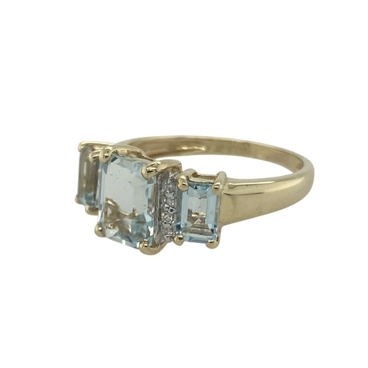 Bring refreshing colour and classic sparkle to your collection with this pre-owned 9ct yellow gold diamond and aqua trilogy ring, designed with elegance and timeless charm.

Design: The ring features three rectangular aqua stones, with the central stone measuring 9mm by 7mm, complemented by two smaller aqua stones on either side and accented with delicate diamonds in between.