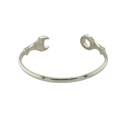 Bring playful style and sparkling detail to your collection with this new 925 silver cubic zirconia spanner torque bangle, a fun and fashionable design for children.

Design: The bangle features a torque style with a spanner-inspired design at the ends, accented with sparkling cubic zirconia stones for a touch of brilliance.
Material: Made from solid 925 sterling silver, the polished finish enhances the shine and gives a modern look.