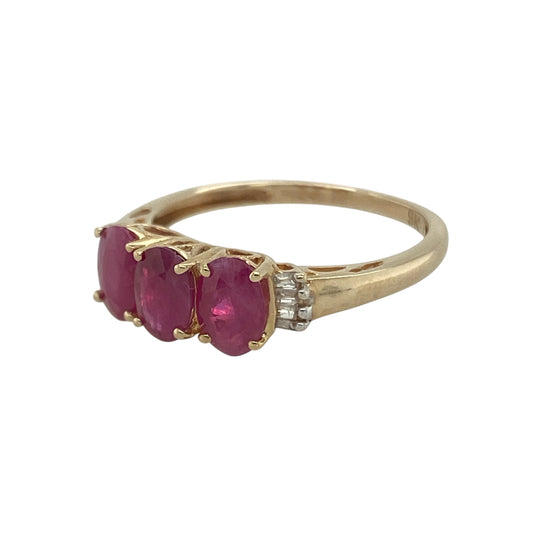 ChatGPT said:

Bring timeless beauty and vibrant colour to your collection with this pre-owned 9ct yellow gold diamond and ruby trilogy ring—a classic design symbolising love, strength, and enduring elegance.

Design: The ring showcases three oval-cut rubies, each measuring 6mm by 4mm, arranged in a traditional trilogy layout that represents the past, present, and future. Baguette-cut diamonds accent the shoulders, adding brilliance and sophistication to the rich red gemstones.