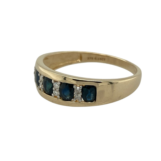 Bring classic elegance and deep colour to your collection with this pre-owned 9ct yellow gold diamond and sapphire band ring—a timeless design that combines rich tones with refined sparkle.

Design: The ring features five oval-cut sapphires across the front, each separated by a small diamond for a touch of brilliance. The arrangement creates a balanced and graceful design that showcases the natural beauty of the gemstones.
