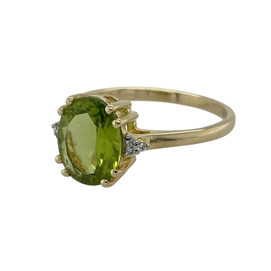 Bring vibrant colour and refined sparkle to your collection with this pre-owned 9ct yellow gold diamond and peridot ring—a classic and elegant piece that radiates warmth and sophistication.

Design: The ring features an eye-catching oval-cut peridot measuring 10mm by 8mm at its centre, displaying a bright green hue full of life and brilliance. Three small diamonds are set on either side, adding subtle sparkle and enhancing the vivid colour of the peridot.