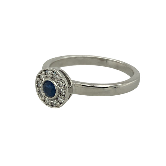 Bring timeless elegance and rich colour to your collection with this pre-owned 18ct white gold diamond and sapphire halo ring—a classic design that exudes sophistication and charm.

Design: The ring features a deep blue round sapphire at the centre, measuring approximately 3mm in diameter, surrounded by a halo of sparkling diamonds that enhance its vivid colour and brilliance. The halo arrangement creates a refined and luxurious look with vintage appeal.