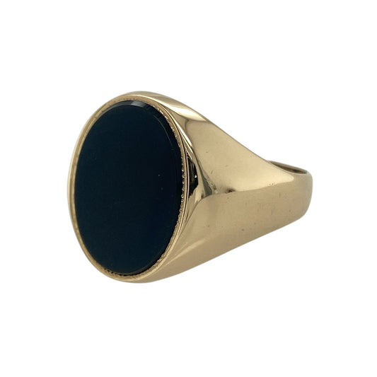 Bring bold sophistication and timeless elegance to your collection with this pre-owned 9ct yellow gold onyx oval signet ring—a classic design that exudes strength and refined style.

Design: The ring features an impressive oval-shaped onyx stone measuring approximately 16mm by 12mm, showcasing a deep black hue with a smooth, polished surface that reflects understated luxury. The sleek design highlights the natural beauty and contrast of the gemstone.