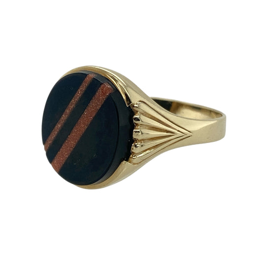 Bring distinctive style and refined elegance to your collection with this pre-owned 9ct yellow gold onyx oval signet ring—a unique design that combines classic craftsmanship with subtle sparkle.

Design: The ring features an oval-shaped onyx stone measuring approximately 14mm by 12mm, detailed with two glittering sandstone stripes that add depth and a touch of shimmer to the bold black surface. The contrast of textures creates a refined and eye-catching look.