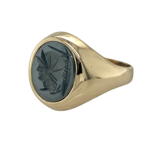 Bring strength and sophistication to your collection with this pre-owned 9ct yellow gold and hematite signet ring, combining classical influence with timeless elegance—perfect for everyday wear or refined occasions.

Design: The ring features an oval hematite stone measuring 12mm by 10mm, intricately carved with a centurion head motif that reflects heritage and character.