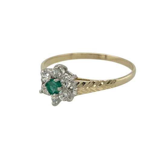 Bring delicate sparkle and vibrant colour to your collection with this pre-owned 9ct yellow gold green stone and cubic zirconia flower cluster ring, combining timeless charm with graceful detail—perfect for adding elegance to any occasion.

Design: The ring features a 3mm emerald-coloured centre stone surrounded by shimmering cubic zirconias in a flower cluster arrangement, with textured shoulders adding an extra touch of character and style.