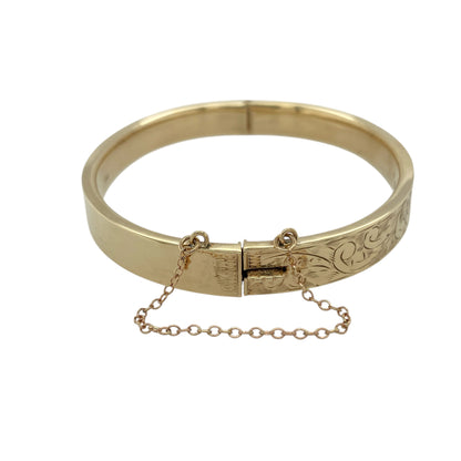 Bring refined elegance and vintage-inspired charm to your collection with this pre-owned 9ct yellow gold patterned hinged bangle, combining timeless design with thoughtful detail—perfect for special occasions or sophisticated everyday wear.

Design: The bangle features an intricate patterned finish across its 8mm width, complemented by a secure hinge fastening and safety chain for added confidence and ease of wear.