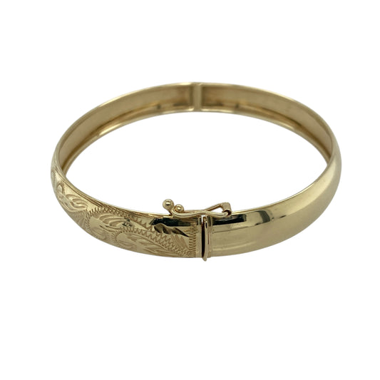 Bring timeless elegance and refined detail to your collection with this pre-owned 9ct yellow gold patterned hinged bangle, combining classic design with a touch of sophistication—perfect for both everyday wear and special occasions.

Design: The bangle features an 8mm-wide band with an intricate patterned finish, adding texture and subtle sparkle to its polished surface. The secure hinged fastening ensures easy wear and a comfortable fit.