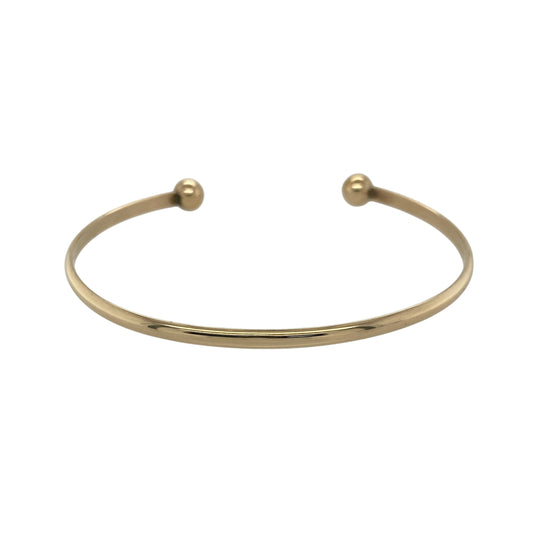 Bring sleek style and classic elegance to your collection with this pre-owned 9ct solid yellow gold torque bangle—perfect for everyday wear or adding a timeless finishing touch to any outfit.

Design: The bangle features a smooth 3mm-wide band finished with two 6mm polished gold balls at each end, creating the signature open torque style. Its simple yet sophisticated design offers versatility and enduring appeal.