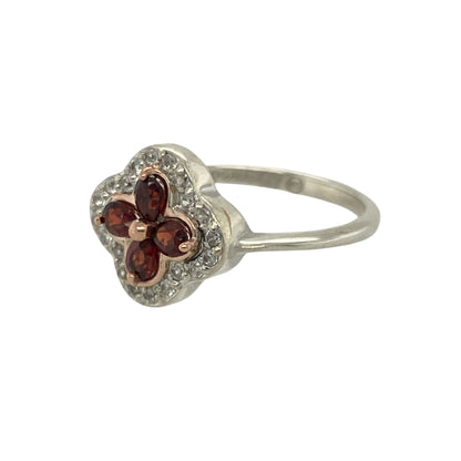 Bring regal elegance and refined sparkle to your collection with this pre-owned 925 silver and 9ct rose gold white topaz and garnet set Clogau Tudor Court flower style ring—perfect for adding a touch of heritage-inspired beauty to any occasion.

Design: The ring features an intricate flower-style design at the front, measuring 11mm high, inspired by the ornate architecture of the Tudor period.