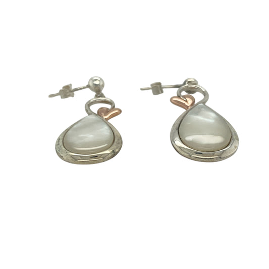 Bring natural beauty and symbolic elegance to your look with these pre-owned 925 silver and 9ct rose gold mother of pearl Clogau Tree of Life style drop earrings—perfect for adding grace and meaning to any occasion.

Design: Each earring features an elegant 13mm by 9mm oval mother of pearl stone, adorned with delicate Tree of Life detailing in warm 9ct rose gold. The lustrous pearl backdrop complements the intricate branches, symbolising growth, renewal, and connection.