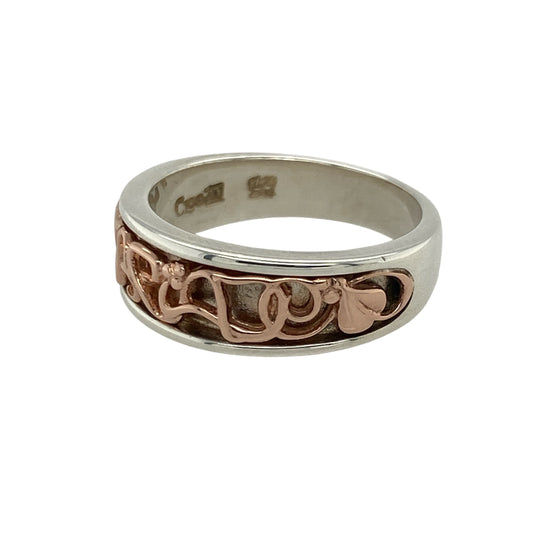 Add heartfelt meaning and classic elegance to your collection with this pre-owned 925 silver and 9ct rose gold Clogau Cariad band ring — a beautifully designed piece that celebrates love and connection.

Design: The ring features the Welsh word “Cariad”, meaning “love”, elegantly incorporated into the design of the 7mm wide front band, symbolising affection and unity.