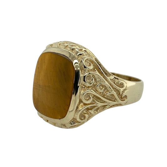 Add bold character and natural warmth to your collection with this pre-owned 9ct yellow gold and tiger’s eye signet ring, showcasing rich golden tones and distinctive detail—perfect for everyday sophistication or standout style.

Design: The ring features a striking rectangular tiger’s eye stone measuring 14mm by 12mm, displaying its signature chatoyant shimmer. The gold surrounding the stone is patterned, adding texture and depth to the classic signet design.