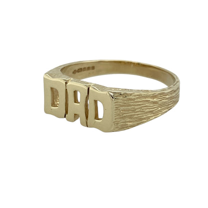 Celebrate sentiment and classic style with this pre-owned 9ct yellow gold Dad ring, a timeless piece that combines bold design with meaningful charm—perfect as a treasured keepsake or thoughtful gift.

Design: The ring features the word DAD across the front, measuring 8mm high, with textured shoulders that add depth and character to the design.
Material: Made from 9-carat yellow gold, the polished finish enhances the warm tone of the metal and gives the piece a refined yet masculine look.