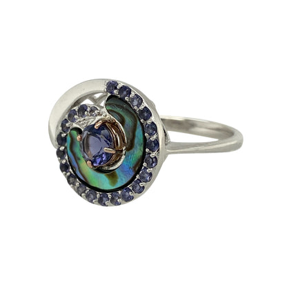 Bring coastal charm and elegant colour to your collection with this pre-owned 925 silver with 9ct rose gold and iolite set Ebb and Flow Abalones Clogau ring—a beautifully designed piece inspired by the movement of the sea.

Design: The ring features a 5mm round iolite stone at the centre, surrounded by flowing silver and rose gold detailing that evokes the rhythm of ocean waves and the organic beauty of abalone shells.
