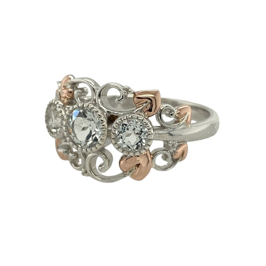 Bring symbolic beauty and radiant sparkle to your collection with this pre-owned 925 silver with 9ct rose gold and white topaz set Clogau Trilogy Tree of Life ring—a meaningful design representing love, strength, and growth.

Design: The ring features a 5mm round white topaz at the centre, framed by Clogau’s signature Tree of Life detailing in warm rose gold, symbolising the harmony between nature and life’s journey.