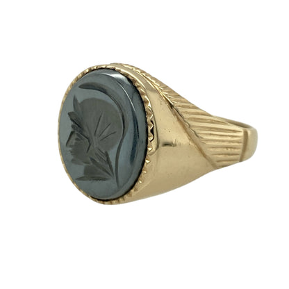 Bring bold character and striking contrast to your collection with this pre-owned 9ct yellow gold hematite centurion signet ring—an impressive piece offering strong presence and timeless appeal.

Design: This size W signet ring features a 14mm by 11mm oval hematite stone engraved with a classic centurion motif, creating a distinctive, detailed focal point with a deep metallic sheen.