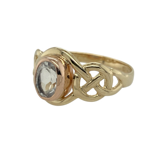 Bring meaningful design and vibrant colour to your collection with this pre-owned 9ct yellow and rose gold Clogau knot ring—an elegant piece offering symbolic style and refined gemstone beauty.

Design: This size M ring features a 7mm by 5mm oval topaz at the centre, framed by a flowing Clogau knot motif that represents unity, continuity, and connection.
Material: Made from 9-carat yellow and rose gold, the warm mixed-metal tones beautifully complement the bright, crisp blue of the topaz.