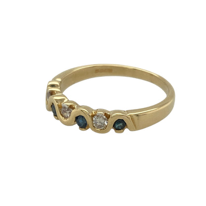 Bring elegant movement and refined sparkle to your collection with this pre-owned 18ct yellow gold sapphire and diamond wavy band ring—an attractive piece offering timeless style and graceful detail.

Design: This size L–M band features a 4mm wide wavy front set with alternating sapphires and diamonds, creating a flowing, light-catching pattern across the ring.