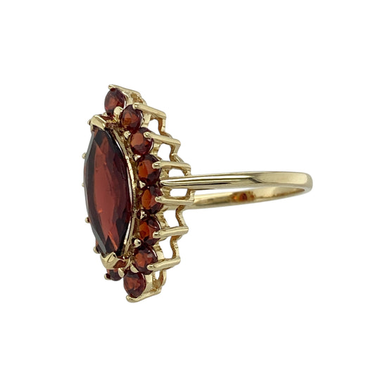 Bring rich colour and vintage-inspired elegance to your jewellery collection with this pre-owned 9ct yellow gold garnet cluster ring — a striking piece with bold presence and warm, luxurious depth.

Design: The ring features a 15mm by 7mm marquise-cut central garnet surrounded by smaller round garnets, creating a dramatic and beautifully balanced cluster arrangement.