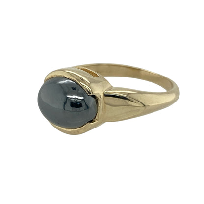 Bring bold depth and sleek elegance to your jewellery collection with this pre-owned 9ct yellow gold hematite ring — a striking piece with strong, modern character.

Design: The ring features a 10mm by 8mm oval hematite stone, offering a smooth, metallic sheen and rich dark tone for an eye-catching focal point.
Material: Made from 9ct yellow gold, the polished finish provides a warm contrast that enhances the cool, reflective surface of the hematite.